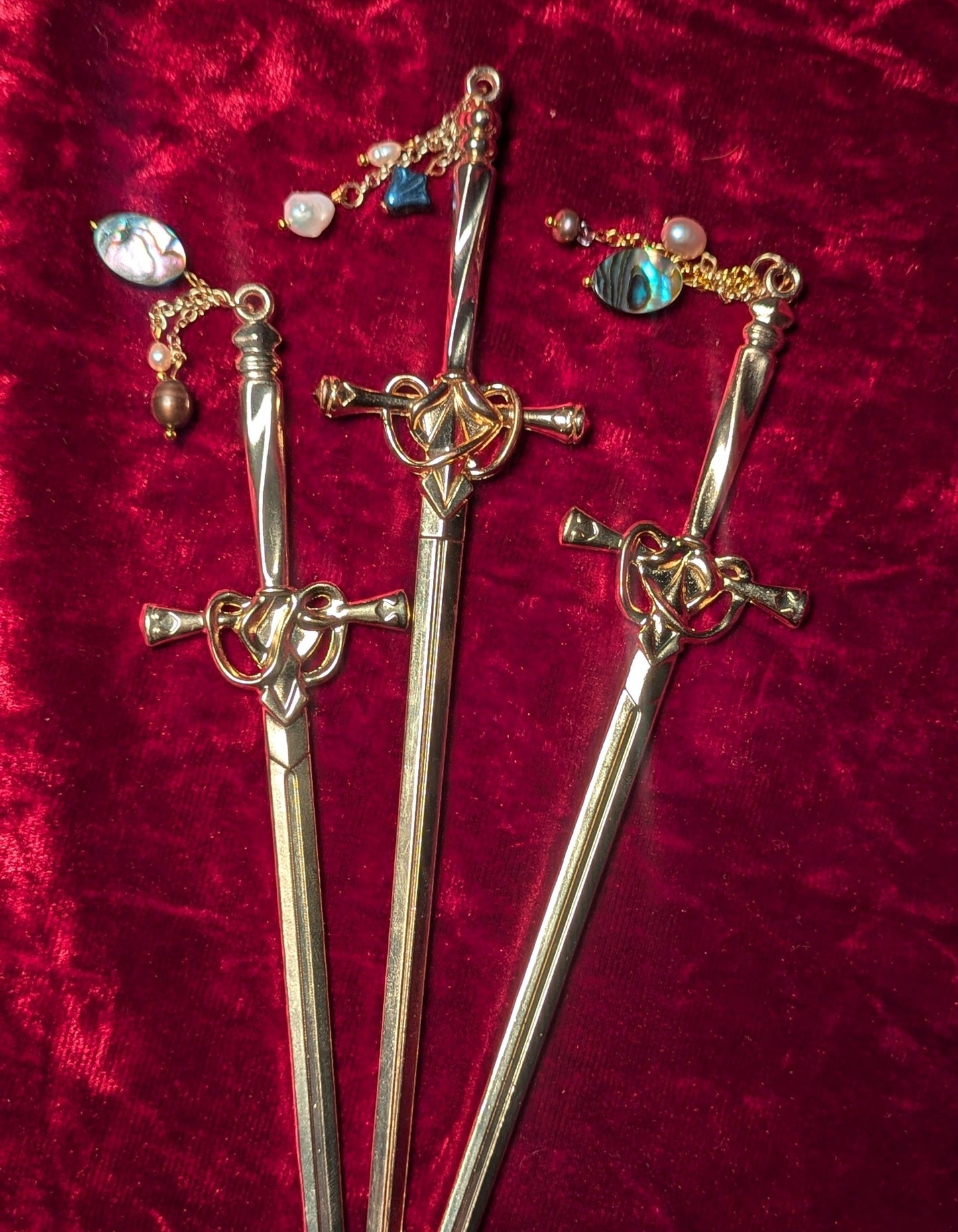 Gold hair sticks with charms on a red textured background